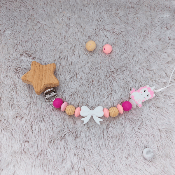 chupetero-unicornio-rosa-lazo-estrella-madera-suelo
