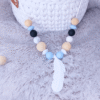 collar-porteo-silicona-pluma-azul-negro-madera-beige